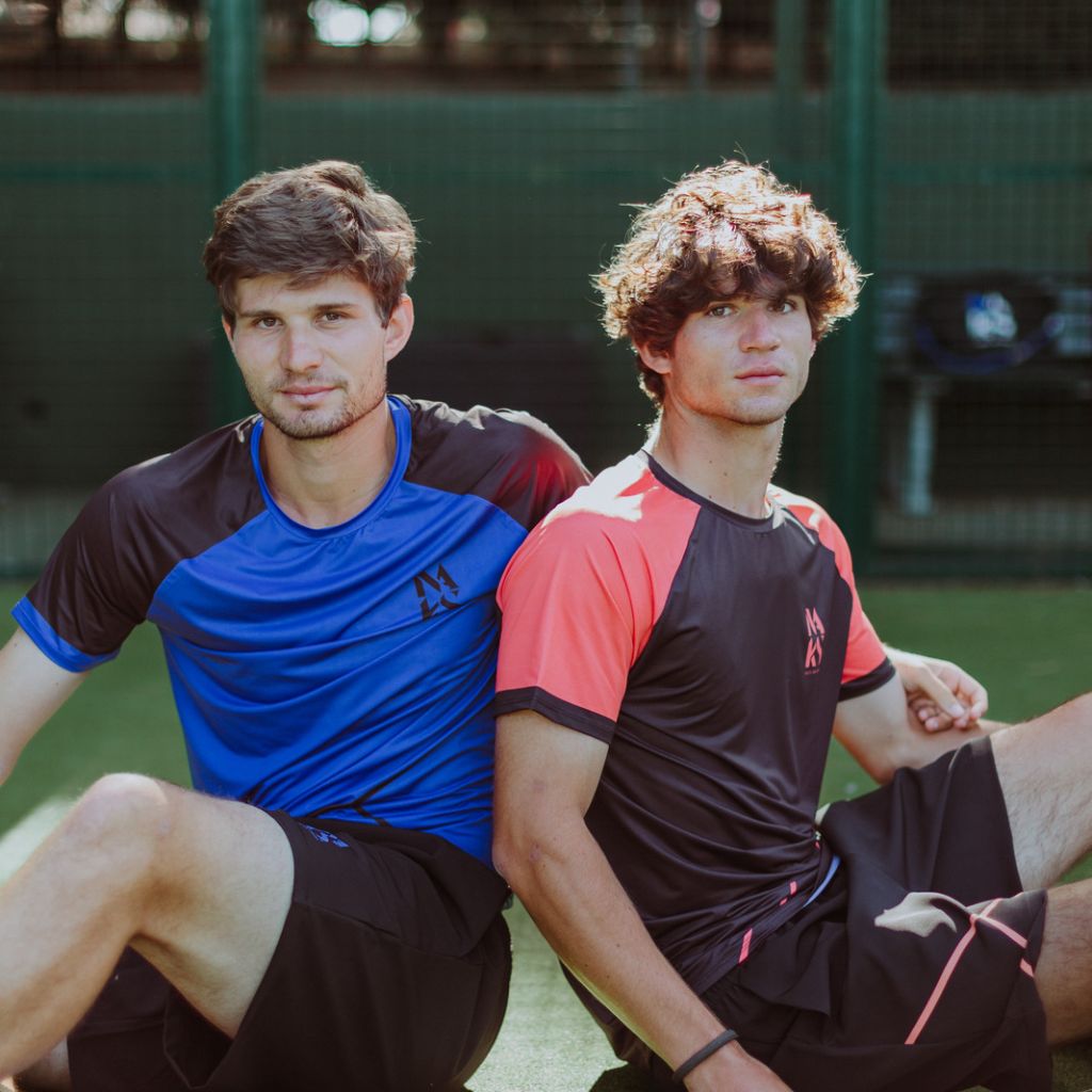 Naks - Hombre Coleccíon por Padel, Tenis y Gym : 2 hombres sentados en una pista de padel, con una camiseta azul y otra naranja